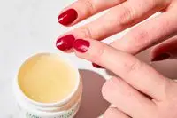 A person applying Mario Badescu Cuticle Cream to their nail bed