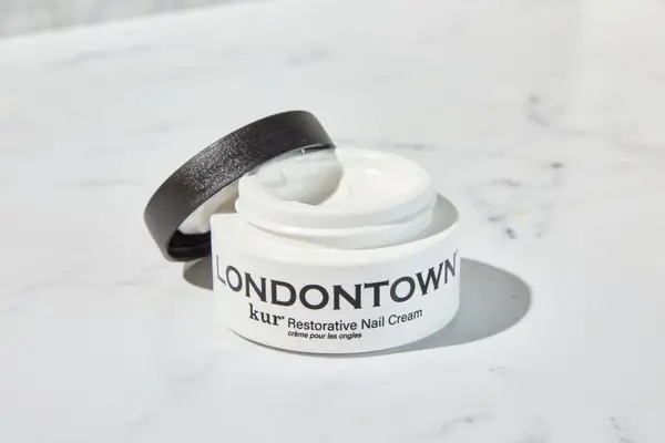 An open container of Londontown Restorative Nail Cream on a marble counter