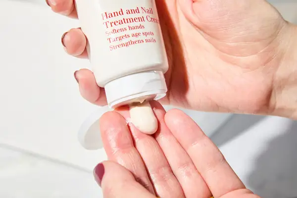 Person dispenses Clarins Hand and Nail Treatment Cream into their hand