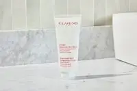 A bottle of Clarins Hand and Nail Treatment Cream on a marble counter