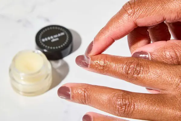 A person applying Beekman 1802 Pure Goat Milk Cuticle Cream to their nail bed