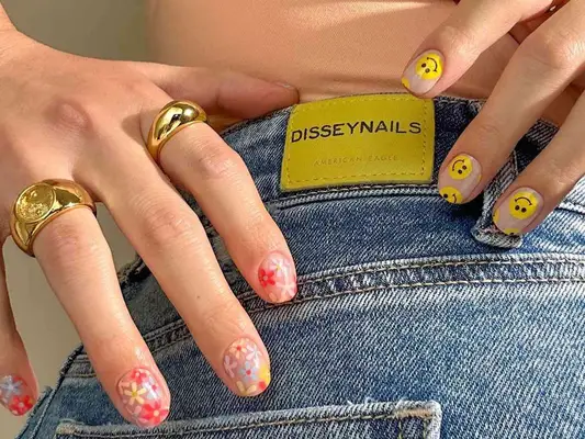 Manicure with one hand of smiley face designs and one hand of floral designs