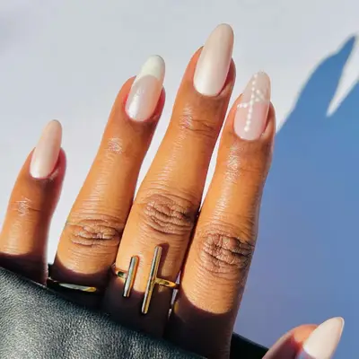 Close-up of manicure with sheer shimmery white base, French tip, and dotted design