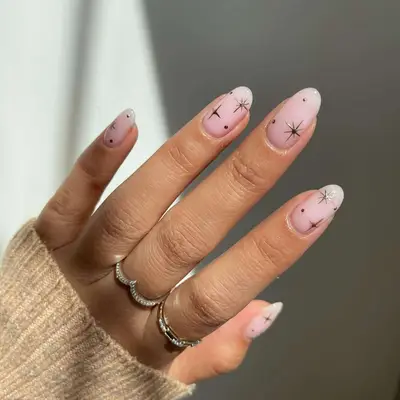 Close-up of manicure with sheer white and pink base and chrome stars design