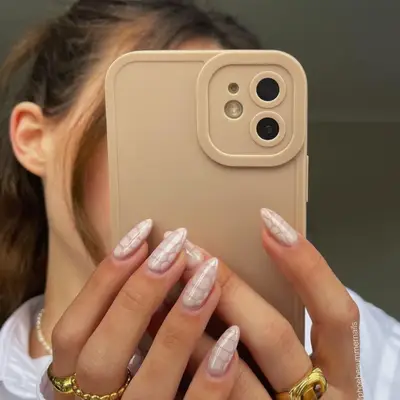 Close-up of person taking mirror selfie with creamy white croc manicure
