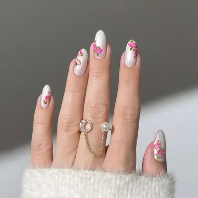 Close-up of manicure with white base and pink floral design