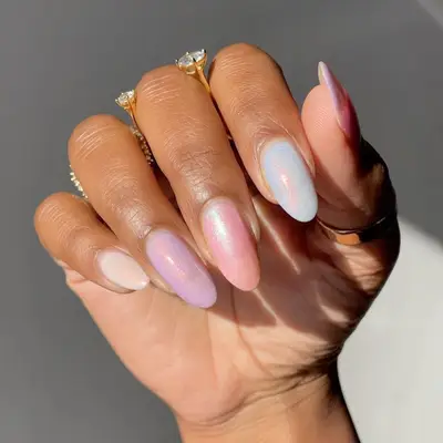 Hand with almond shaped nails, multi-colored pastel polishes and a peach chrome finish.