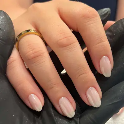 Hand with almond shaped nails with a transparent base coat and chrome finish.