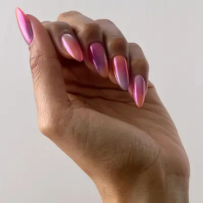 Hand with almond shaped nails with a pink, orange and purple tie-dye pattern with a chrome finish.