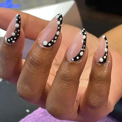 Close up of a polka dotted, black stripe nail look