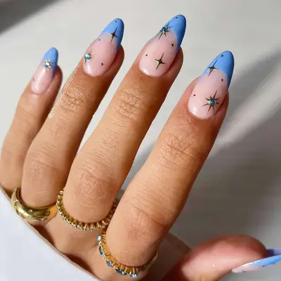 Close up of a manicure with baby blue French tips and celestial details