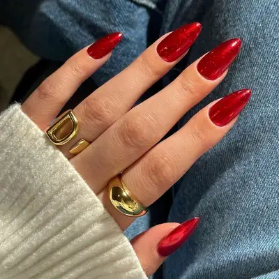 A red chrome manicure held over jeans