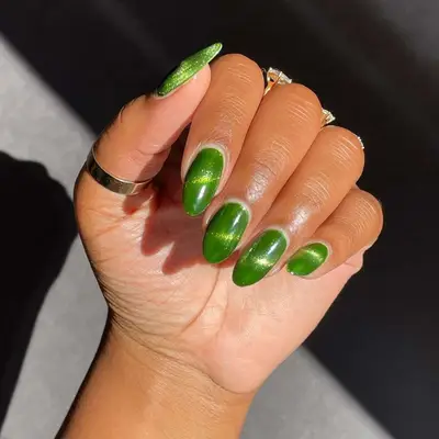 A green cat-eye magnetic manicure, hand with fingers toward the palm