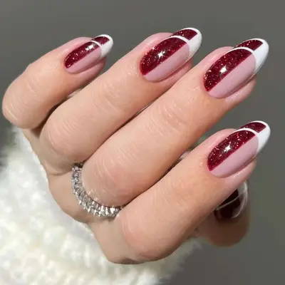 a manicure that is half pinky nude, half red glitter with white french negative-space tips