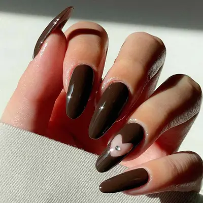 brown manicure with heart negative space and gem on ring finger