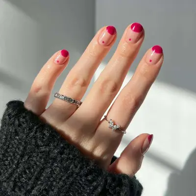Manicure with berry jam colored half-moon at tip and dot near cuticle over neutral base