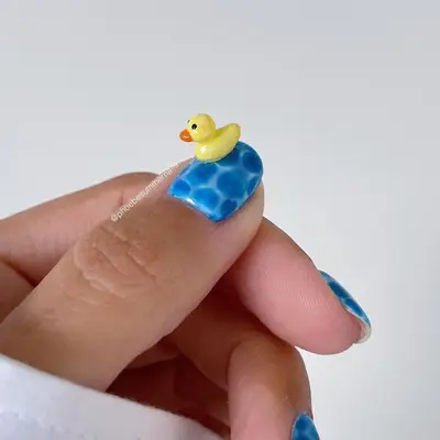 A blue, water-inspired nail with a 3D rubber ducky accent
