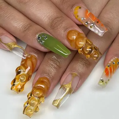 A manicure with 3D details in shades of honey, green, and orange