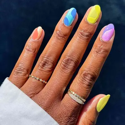 A manicure in raninbow shades, with monochrome swirls on each finger