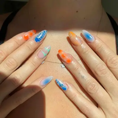 A manicure with various chrome and prints in oranges and blues