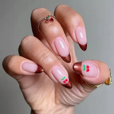 a metallic brown french manicure topped with cherry accents