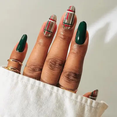 dark green nails with gold, red, and white accent nails