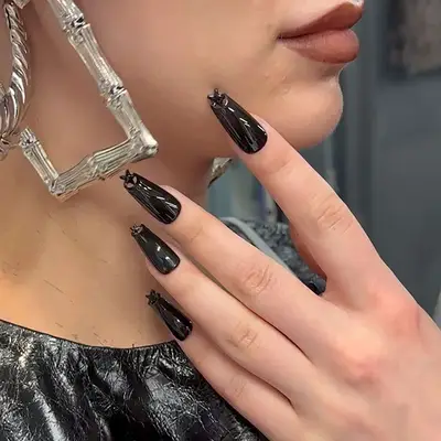 A long glossy black manicure with star cutouts on the tips
