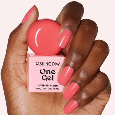 A hand holding a bottle of Dashing Diva One Gel nail polish with nails painted a matching color