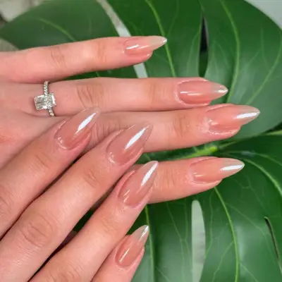 Glossy peach manicure on short stiletto-shaped nails.
