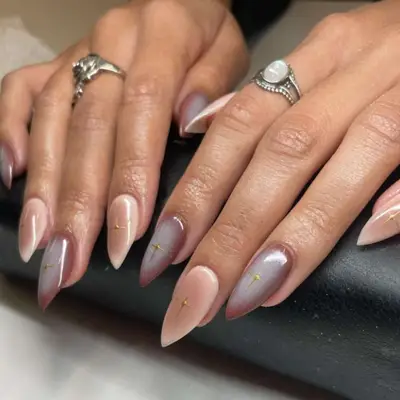 Aura manicure nail design using nudes and browns on short, stiletto-shaped nails.