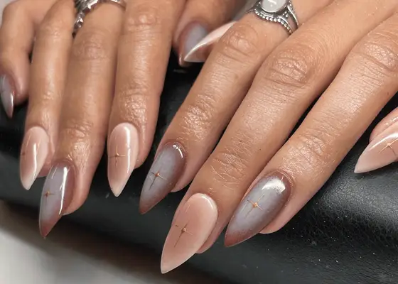 Aura manicure nail design using nudes and browns on short, stiletto-shaped nails.