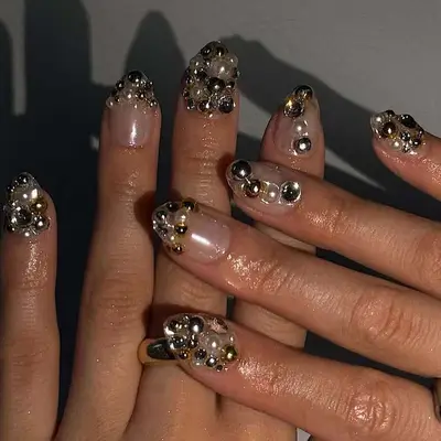 Hands showing nails adorned with gemstone and metallic embellishments