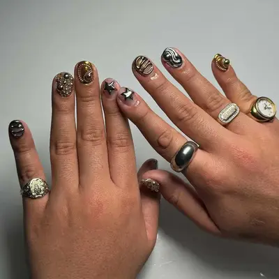 Stylized and decorative manicured hands with artistic designs on nails, wearing various rings
