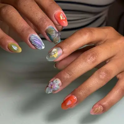 Hands showing creatively painted nails with intricate designs and patterns