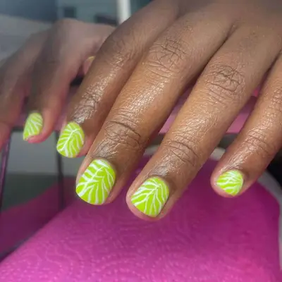 Close-up of a hand with nail art featuring leaf patterns on the nails