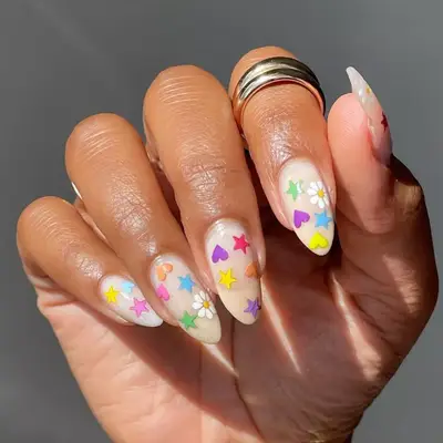 nails with 90s vibes stickers like hearts, stars, flowers in bright colors