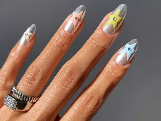 Manicure with chrome base, multicolored pastel star designs, and gem accents