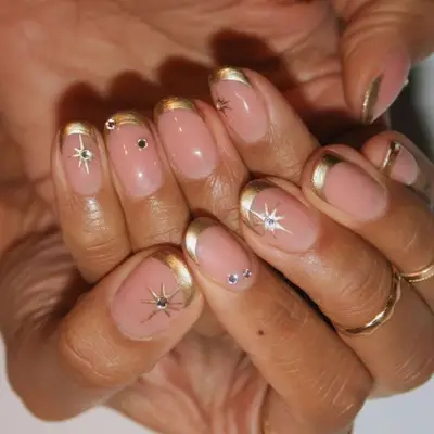 Metallic gold French manicure with rhinestone and gold star accents
