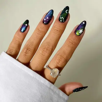 Shade shifting black, blue, purple, and green velvet zodiac nails with white astrology accents