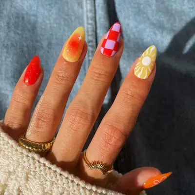 Mismatched Aries manicure featuring bright orange, yellow, red, and white nail art