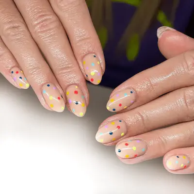 Nude nails with rainbow polka dots.
