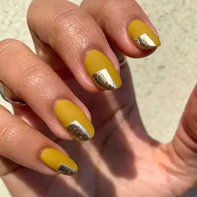 Mustard yellow manicure with chrome metallic nail design in corner