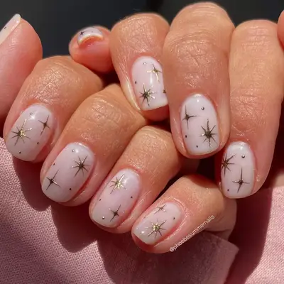 milky manicure with gold sparkle design
