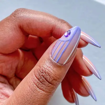 Hand showing nail art with a lilac design, a gem accent, and a smooth background