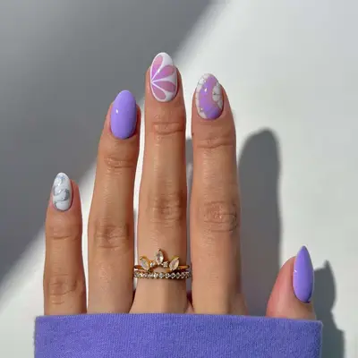 A hand showing lavender and white manicured nails with a mix and match design