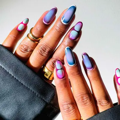 Hands displaying nail art with futuristic colorful patterns, against a neutral background