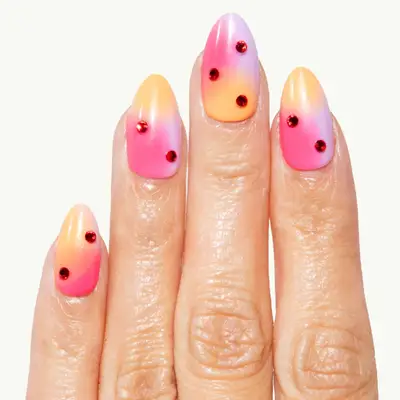 Hand with ombre nails decorated with red gems