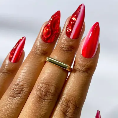 Manicured nails with a glossy and textured finish, featuring an artistic pink and red design, a gold ring on one finger