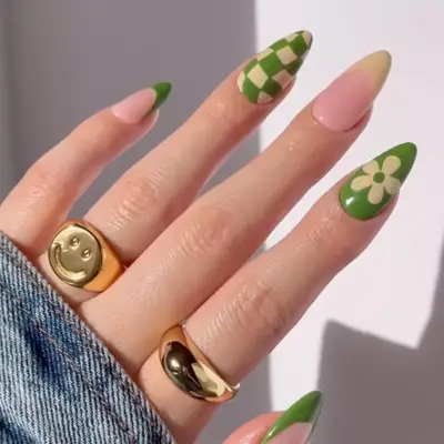 Hand with gold rings and manicured nails featuring green designs