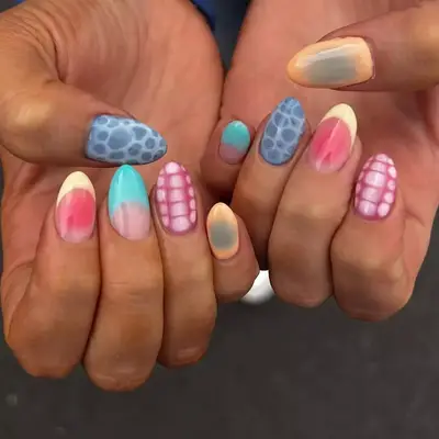 Hands with colorful, patterned manicured nails, including gradients and geometric designs, displayed prominently